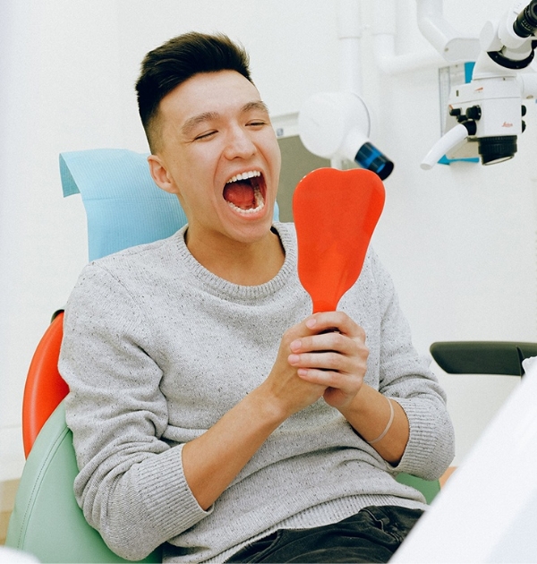 Man looking in mouth using a hand mirror