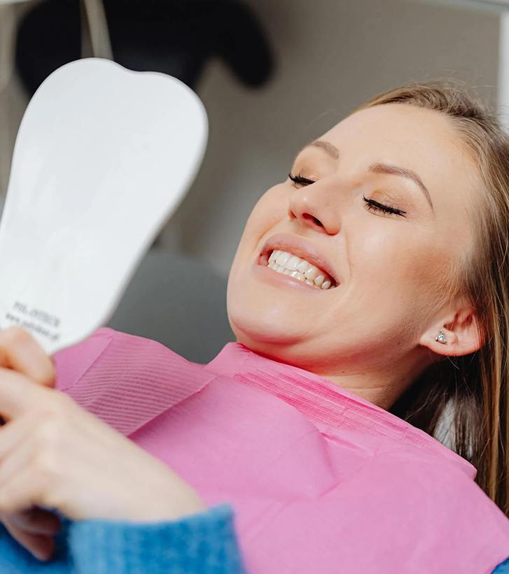 Woman looking at her teeth in a hand mirror