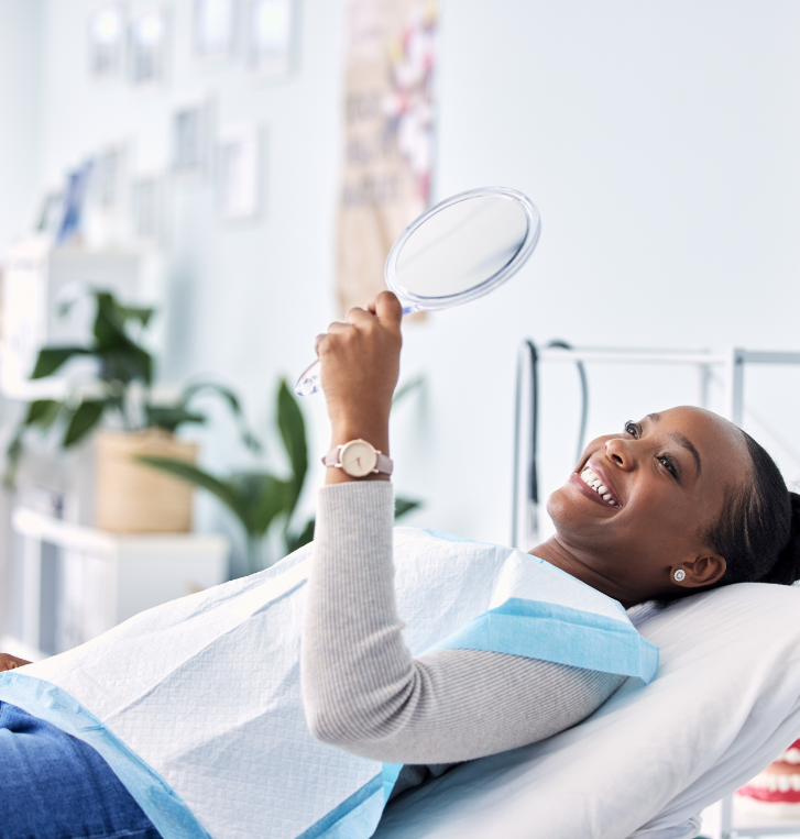 Woman admiring her smile in a mirror while visiting dentist in Beaverton